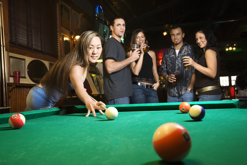 Young woman preparing to hit pool ball while playing billiards.
